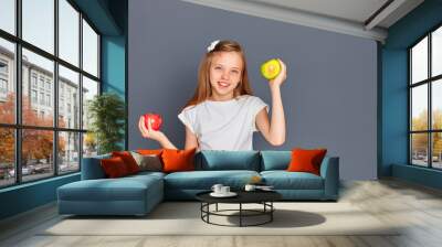 Funny teen girl deciding between a red and green Apple, on a gray background, place for text Wall mural