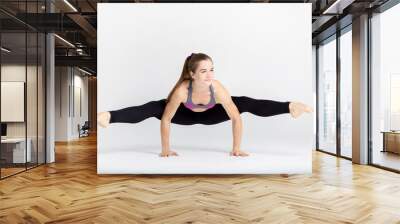 Young sportwoman stretching muscles on white background Wall mural