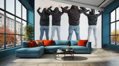 three women and one man in company clothes with black hoodies and jeans stand with their backs to th Wall mural