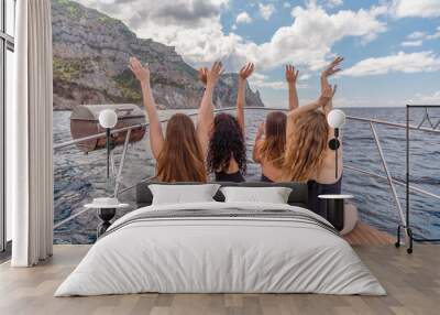 Womans on a yacht. Happy models in a swimsuit posing on a yacht against a blue sky with clouds and mountains Wall mural