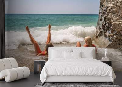 Women ocean play. Seaside, beach daytime, enjoying beach fun. Two women in red swimsuits enjoying themselves in the ocean waves. Wall mural