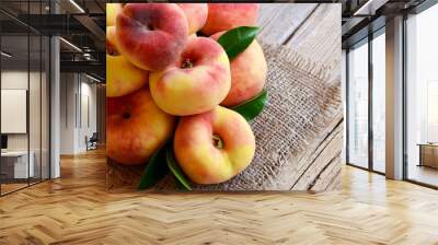 Chinese flat donut peaches with leaves on on old wooden table also known as  Saturn donut, Doughnut peach,
Paraguayo.Healthy eating or diet concept.Selective focus. Wall mural