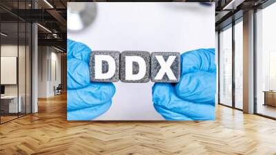 DDX Differential diagnosis - word from stone blocks with letters holding by a doctor's hands in medical protective gloves Wall mural