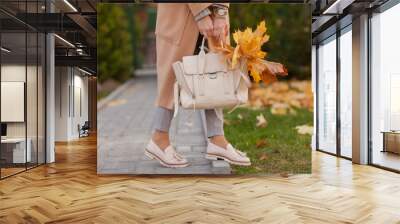 Stylish beautiful woman walking on the street wearing a beige coat, a bag, a warm sweater, a fashionable outfit, an autumn trend, accessories Wall mural