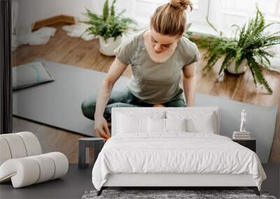 Young relaxed woman doing yoga at home with candles and incense Wall mural