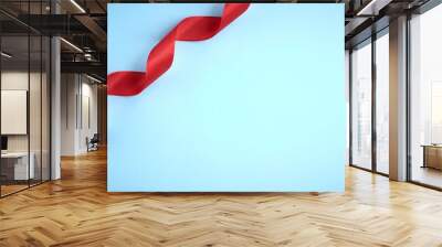 Red ribbon on blue background composition, flat lay Wall mural