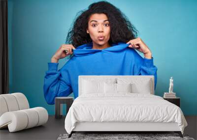 A funny teenage girl in a casual blue sweatshirt making grimaces. Wall mural