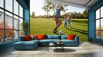 A nurturing and creative world. Happy family playing with a ball on meadow Wall mural