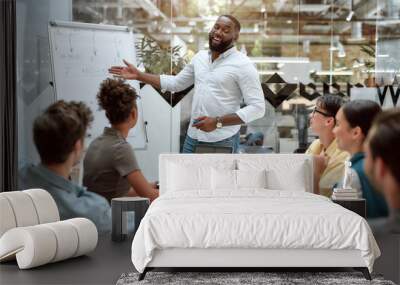 Achieving best results together. Young afro american businessman pointing at white blackboard and smiling while working with multicultural team in the creative office Wall mural