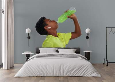 After training. Side view of a teenage african boy wearing neon t shirt drinking green energy drink Wall mural