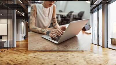 Busy lady. Cropped photo of young tattooed businesswoman using laptop while working in the modern office Wall mural