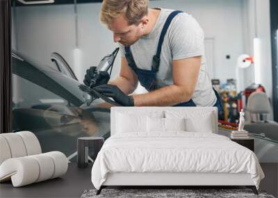 Car service technician checks crack on car windshield closeup Wall mural