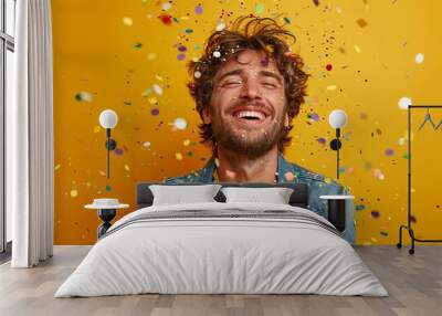 Cheerful man celebrating with confetti against yellow background Wall mural