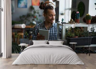 Cheerful man using digital tablet computer and checking plants Wall mural