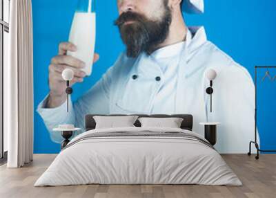 Chef with serious face in white apron and hat holds glass bottle fresh milk. Healthy soy milk, nutritious and delicious milk substitute. Restaurant dairy meal concept. Concept of cooking food. Wall mural