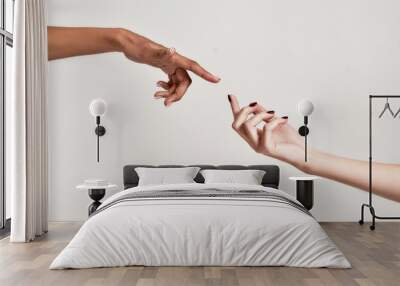 Close up of two hands of diverse women reaching for each other isolated over grey background Wall mural