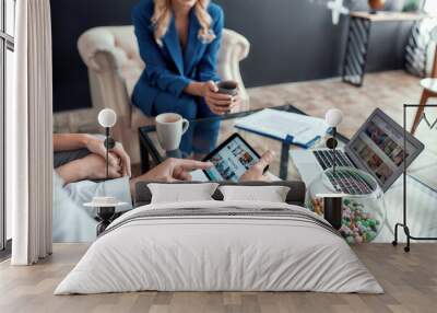 Close up shot of male client holding tablet pc while planning summer vacation with his wife, sitting in modern travel agency office Wall mural