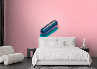 Creative concept with blue glitter pill isolated on pastel pink background. Minimal style, art concept Wall mural