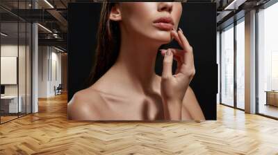 Cropped portrait of delicate brunette woman with pouty lips and professional makeup posing isolated over black background Wall mural