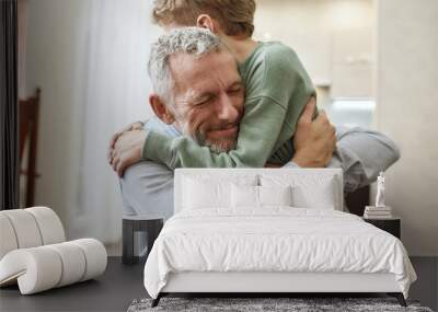 Emotional meeting. Happy grandfather embracing his cute little preschool grandson while standing together at home Wall mural