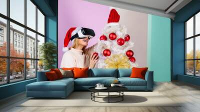 Festive season. Christmas mood. Happy woman in near Christmas tree. Technology, augmented virtual reality, VR, winter, Christmas concept. Smiling girl in virtual reality glasses. New Year, Christmas. Wall mural