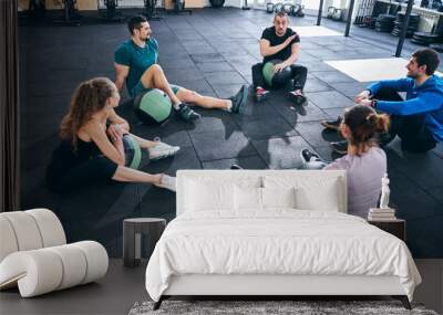 Four athletes listening to their fitness coach Wall mural