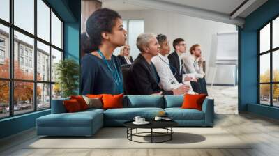 Get Together. Multi-ethnic audience sitting in a row while listening to presentation at conference hall Wall mural