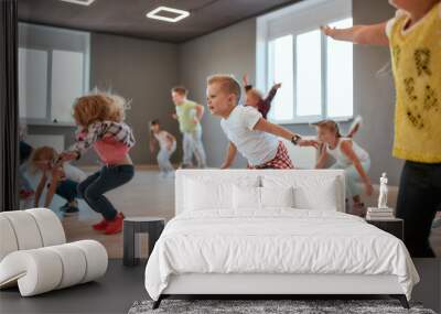 Group of cute little boys and girls studying modern dance in studio. Children jumping while having a choreography class Wall mural