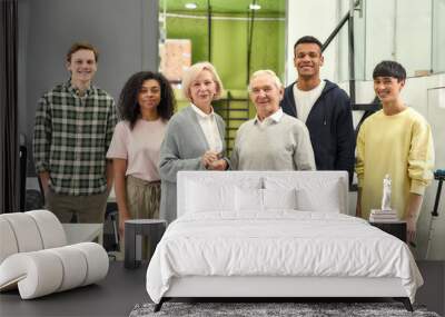 Happy diverse team of employees smiling at camera while posing with senior female and male interns, standing together in the office, Age diversity in the workplace Wall mural