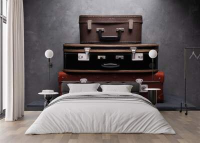 Heap of suitcases on table. Old suitcases near wall as travel concept idea Wall mural