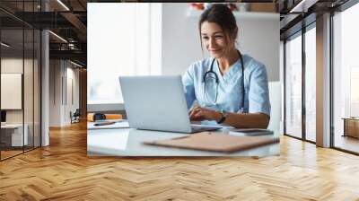 Joyful female doctor using notebook in clinic Wall mural