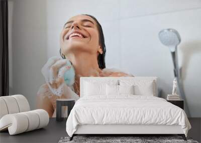 Joyful young woman washing her body with bath loofah Wall mural