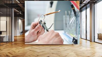 Male optician hands repairing eyeglasses in workshop Wall mural