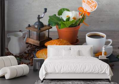 Morning still life concept. Coffee grinder, two buttery croissant , aroma coffee and flowers of primula on wooden background. Wall mural