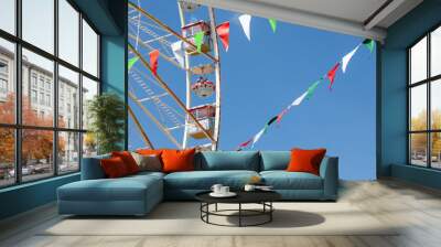 Ferris wheel against the blue sky and garlands with colored flags Wall mural