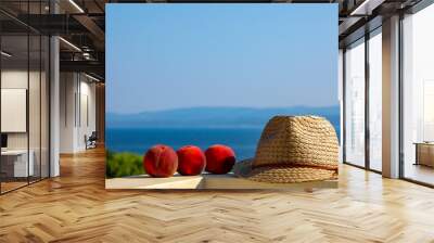 Peaches and wicker straw hat in summer on the edge of a balcony with a beautiful view of the Adriatic Sea in Croatia. Wall mural