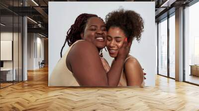 Portrait of happy friends, african american women in underwear with different body size smiling, hugging each other while posing together isolated over gray background Wall mural