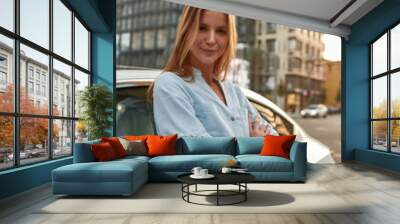 Portrait of happy young caucasian girl standing near car Wall mural