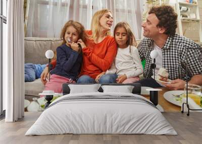 Portrait of smiling parents sitting with daughters and having fun Wall mural