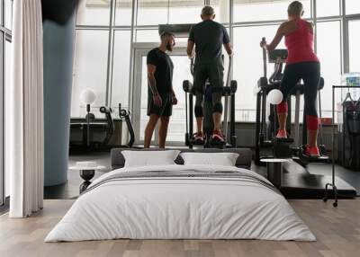 Seniors exercising on step machine with personal trainer Wall mural