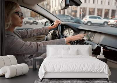 Smart parking. Side view of focused business woman using parking assist system while driving a car Wall mural