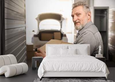 Smiling man in storage unit holding carton box Wall mural