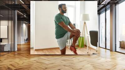 Start your day with fitness. Young active man looking away, stretching his legs during morning workout at home Wall mural