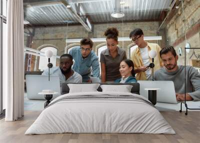 Successful multicultural team. Young business people in casual wear using modern technologies and working together on new project while sitting in the creative office Wall mural