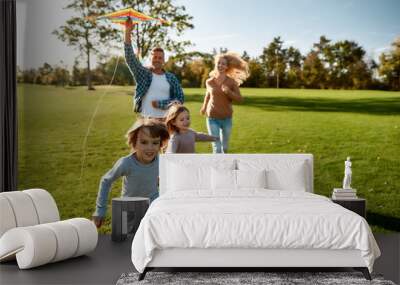 There are no words to describe how special kids are. Happy family playing a kite. Outdoor family weekend Wall mural