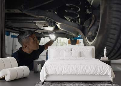 Young asian mechanic with flashlight looking for damages Wall mural