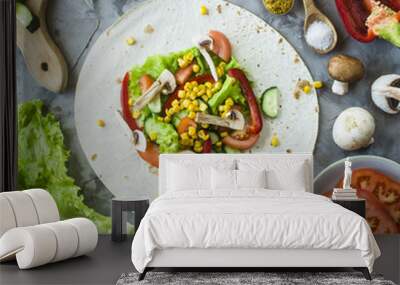 Mexican vegan burrito cooking - vegetables and mushrooms on tortillas on a gray kitchen table. Top view Wall mural