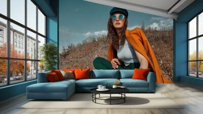 Autumn fashion. Beautiful attracrive young woman in bright autumn look. Orange trendy coat and pants and fashion sunglasses. Wall mural