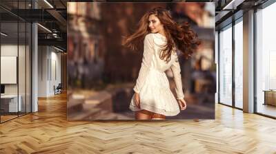 Beautiful young girl with long healthy hair, nice dress walking in the street. Lifestyle concept. Youth and happiness. Wall mural