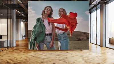 High fashion portrait of two stylish beautiful woman in trendy jackets and jeans posing outdoor. Vogue style. Wall mural